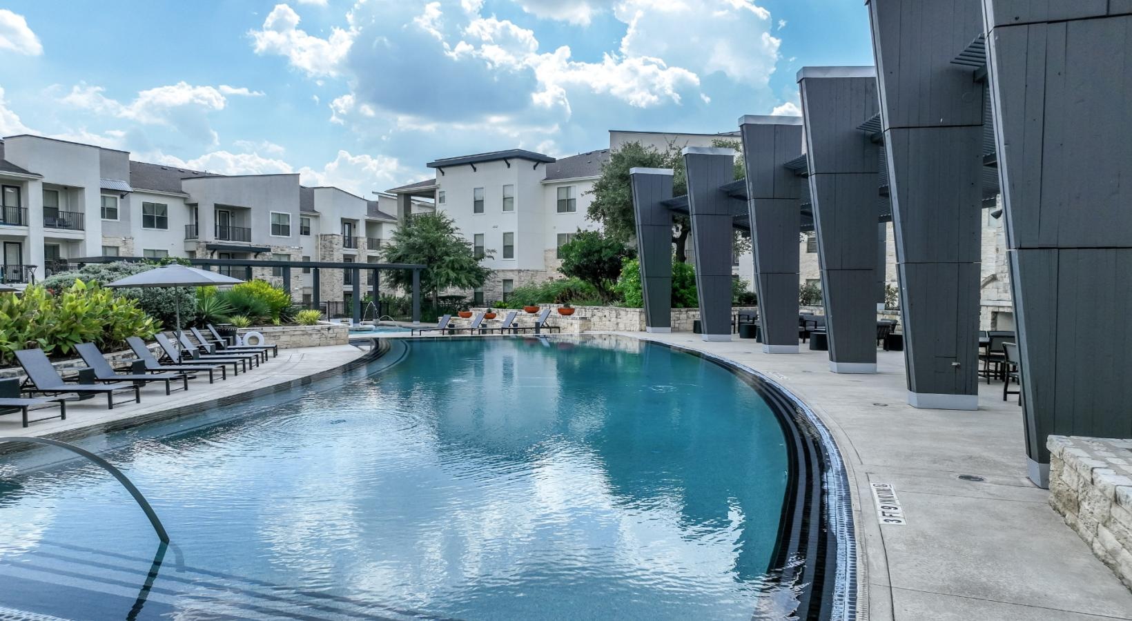 Shimmering resort-style pool a pool in a courtyard with buildings in the background