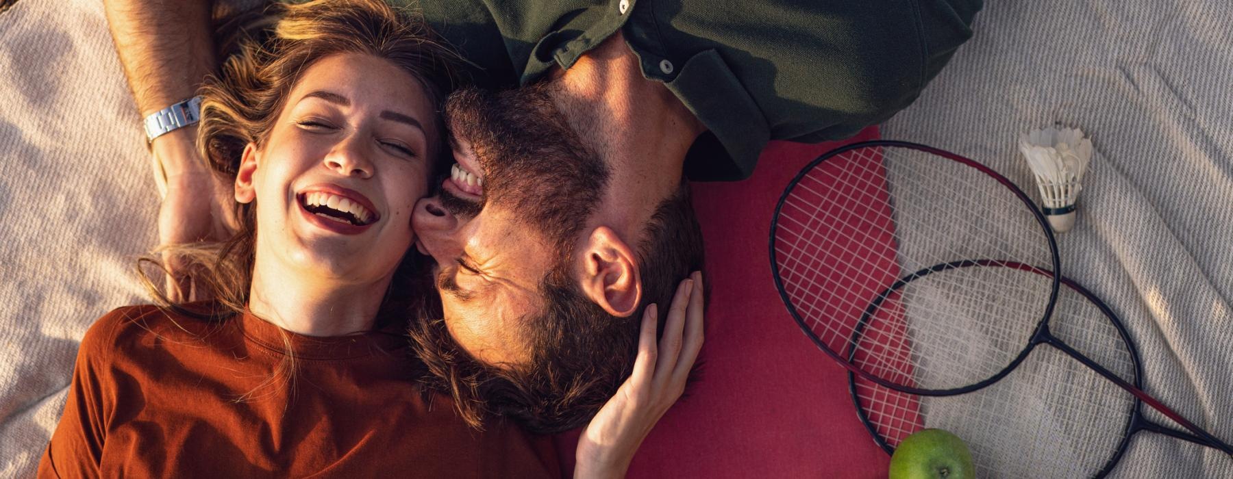 a man and a woman lying on the ground with a ball and a string of fruit